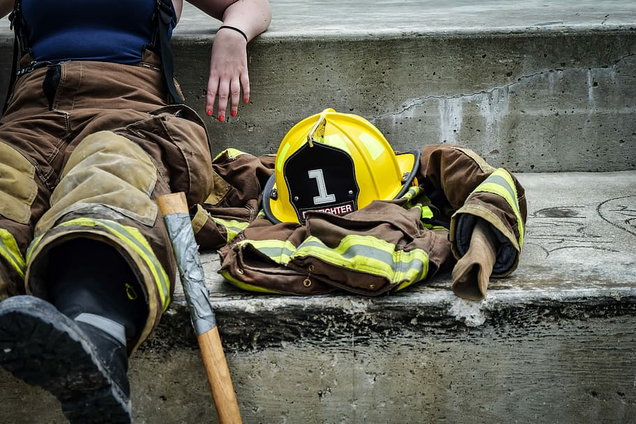 Person, brown, yellow, firefighter suit seating, concrete, ground ...